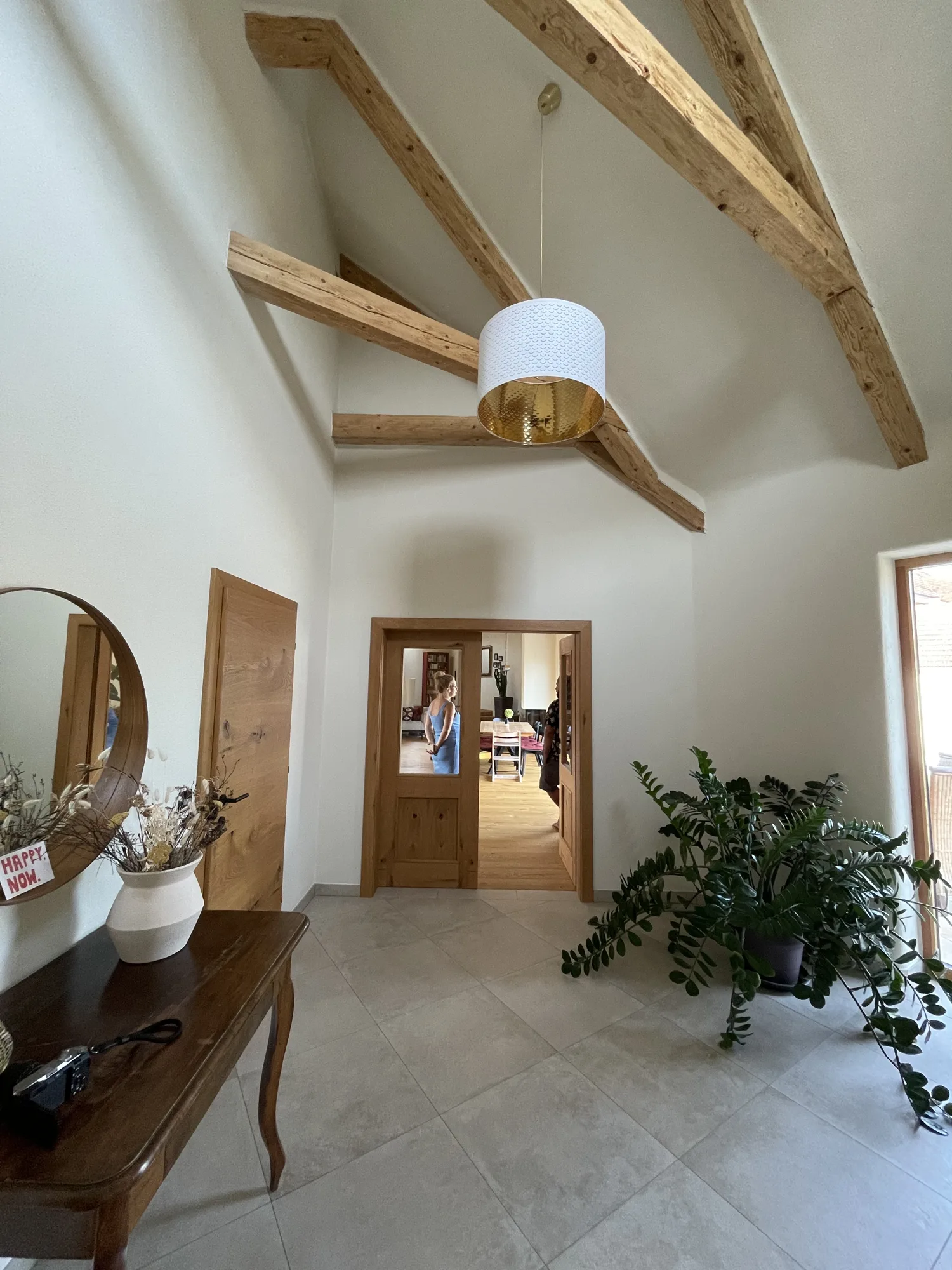 Eingangsbereich mit Holzbalken, Lehmputzwand und Holztür.